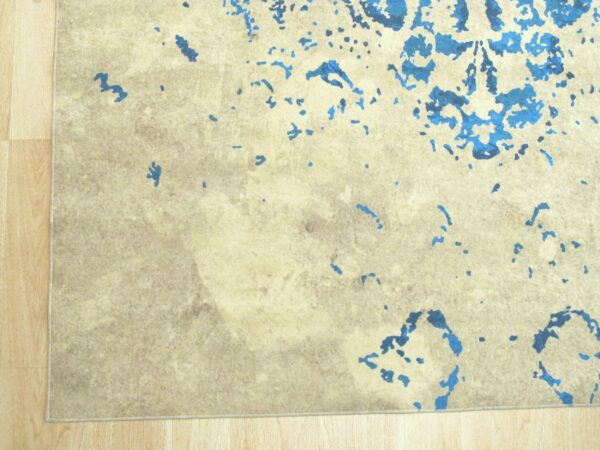 Abstract blue shapes accent a textured beige rug lying on light wood flooring.