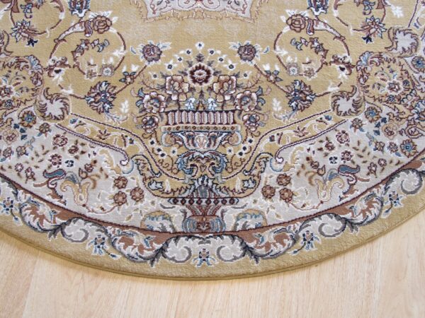 Rounded edge of a beige traditional rug featuring an elaborate floral vase pattern on light wood flooring.
