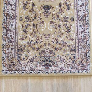 Low-pile traditional tan rug with brown, cream, and blue accents, displayed on light wood plank flooring.