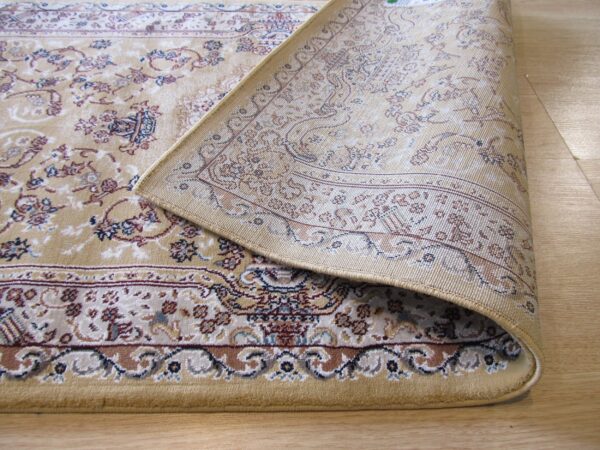Beige traditional rug with floral motifs in red and blue, curled back to show the tightly woven underside on wood.
