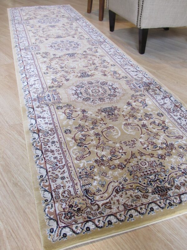 Traditional runner rug in tan, cream, and rust colors lies on light wood flooring next to a chair.