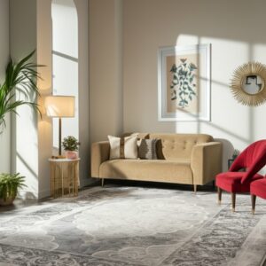 Distressed grey traditional rug on a dark wood floor beneath a beige sofa and two red accent chairs.