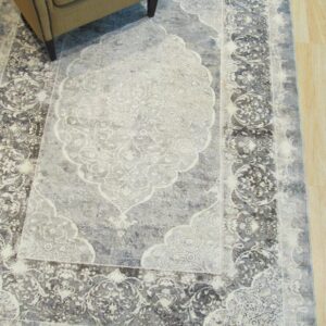 Distressed gray and charcoal medallion rug partially visible under a tan chair on light wood floors.