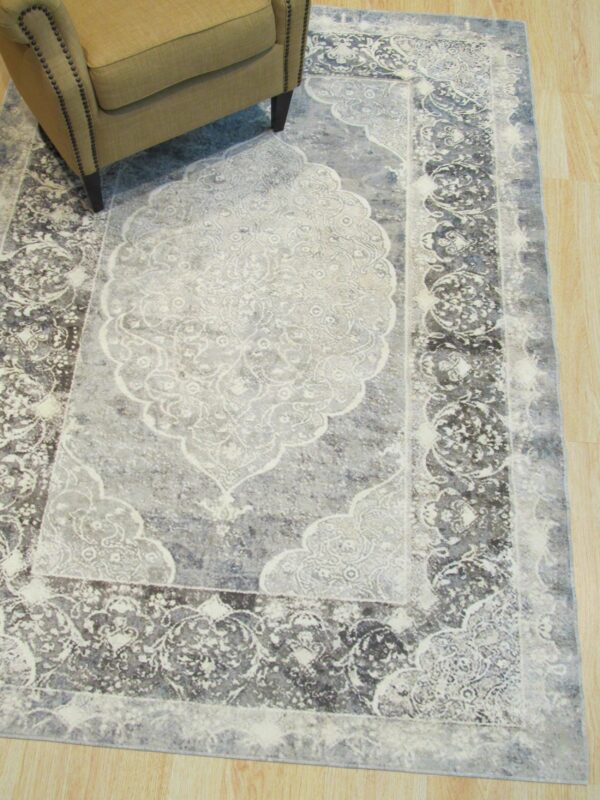 Distressed gray and charcoal medallion rug partially visible under a tan chair on light wood floors.