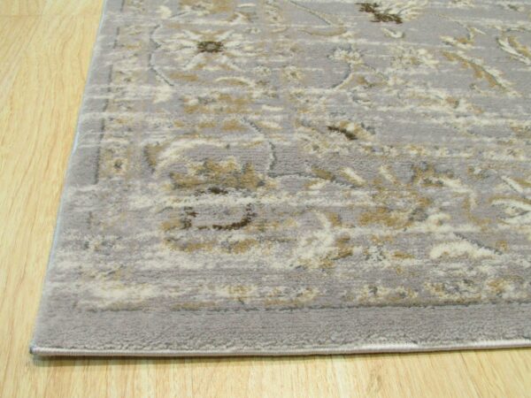 Low-pile gray rug featuring distressed cream and tan classical patterns on light wooden flooring.