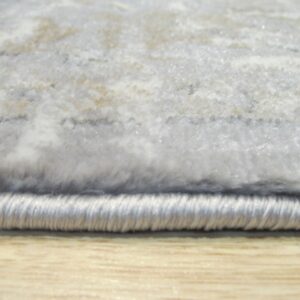 Soft gray and white abstract high-pile rug with bound edge rests on light wood grain flooring.
