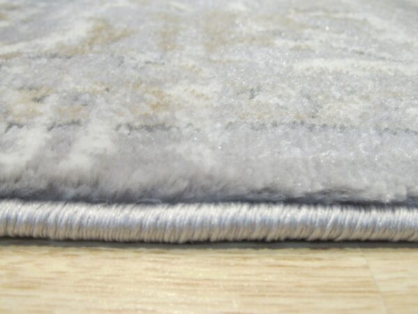 Soft gray and white abstract high-pile rug with bound edge rests on light wood grain flooring.
