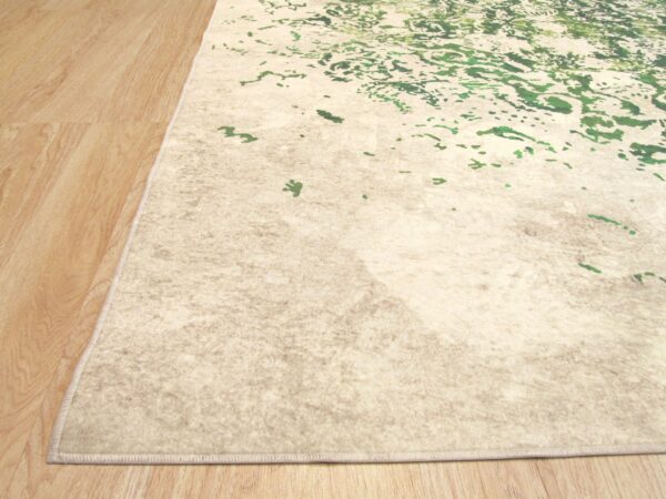 Beige abstract rug with green highlights lies on light brown wood plank flooring.
