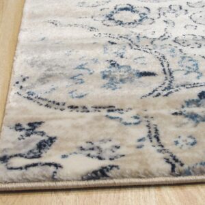 Close-up of a cream rug with navy and light blue distressed patterns resting on light wood flooring.