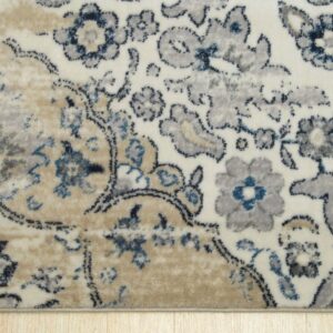 Cream rug with distressed gray, navy, and beige floral patterns rests on light wood flooring.