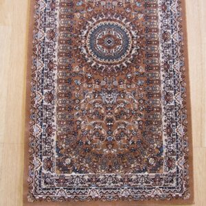 A narrow brown runner rug featuring a detailed traditional medallion pattern in cream and blue rests on light wood flooring.