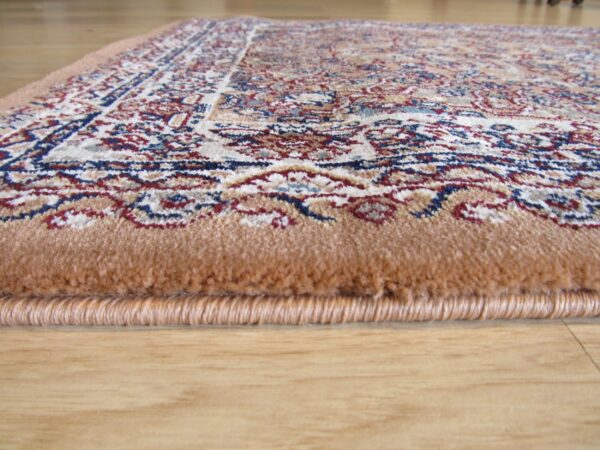 Close-up showing the tan edge, high pile, and traditional red, blue, and cream pattern on wood flooring.