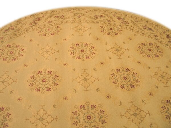 Round gold rug with a low pile features a repeating pattern of burgundy, green, and tan floral designs.