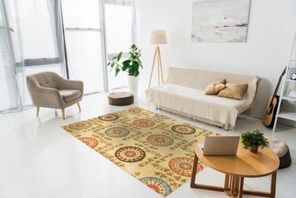Yellow rug with large red, blue, and brown medallions in a bright room with a sofa and armchair.