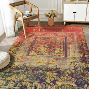 Red and yellow abstract rug with a central medallion on wood flooring next to a wooden chair.