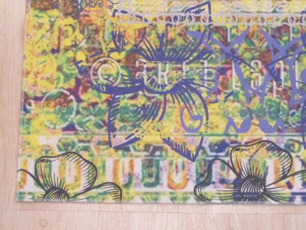 Multi-colored abstract rug featuring yellow, green, and bold purple floral designs on light wood flooring.