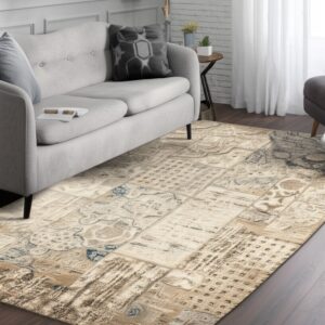 Light beige and brown patchwork rug with distressed blue details under a gray sofa on wood floor.