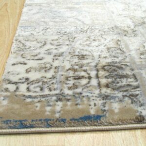 Beige and cream distressed rug with blue accents lies on light wood plank flooring.