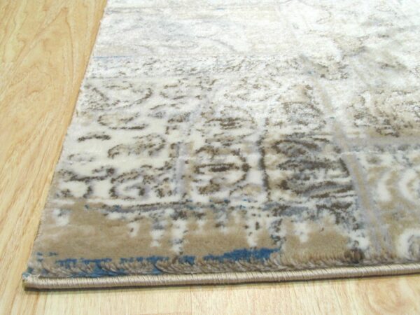 Beige and cream distressed rug with blue accents lies on light wood plank flooring.