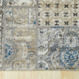 Distressed, low-pile rug fragment in cream, tan, grey, and teal blue over light wood planks.