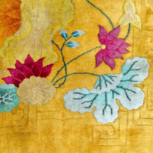 Plush yellow rug detail showing sculpted floral patterns in pink, light yellow, teal, and green.