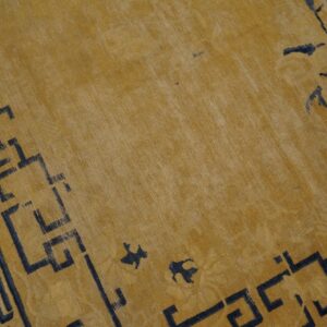 Golden yellow low-pile rug detail with dark geometric border and scattered abstract motifs.