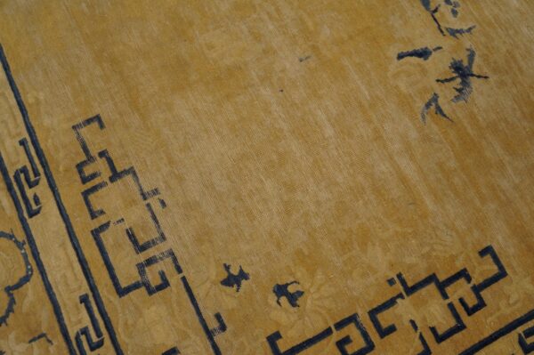 Golden yellow low-pile rug detail with dark geometric border and scattered abstract motifs.