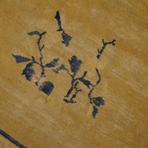 Golden yellow woven rug with dark blue abstracted floral designs and highly visible texture.