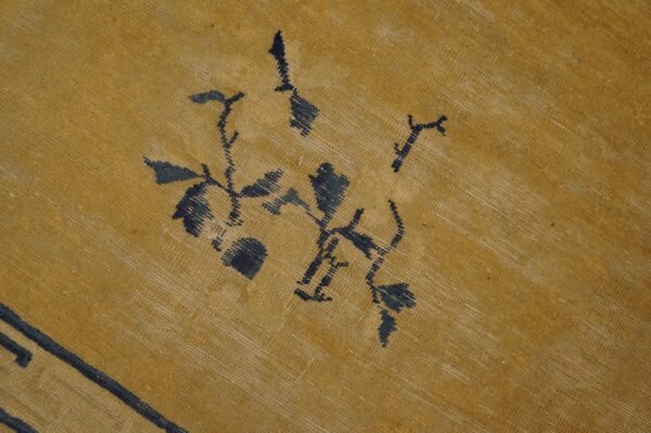 Golden yellow woven rug with dark blue abstracted floral designs and highly visible texture.