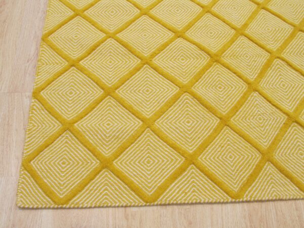Yellow rug featuring a high-contrast concentric diamond pattern within a raised mustard grid on light wood flooring.
