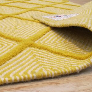 Bright yellow and white rug with carved geometric diamond patterns, partially rolled on light wood flooring.