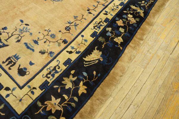 Tan and deep blue floral rug border with medium pile rests on light-colored wood plank flooring.