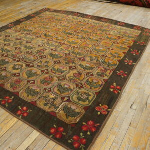 Brown border rug with a repeating golden honeycomb pattern of stylized pink and green flowers on wood flooring.