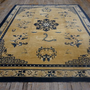 Golden rug with navy blue floral and geometric patterns displayed on rustic wooden flooring.