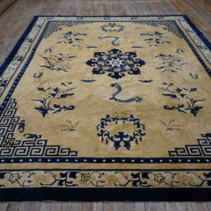 A high-pile tan and navy rug featuring a medallion and Greek key border on rustic wood floors.