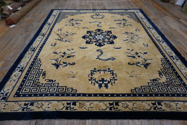 A high-pile tan and navy rug featuring a medallion and greek key border on rustic wood floors.