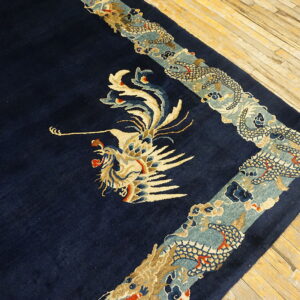 Detailed navy rug with beige and teal dragon and bird motifs on light plank wood floors.