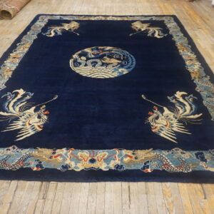 Large navy rug with beige and pale blue dragon and phoenix motifs lies on wood plank flooring.