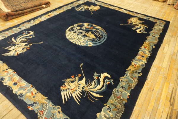 Navy blue rug with a cream dragon medallion and bird figures lies on glossy yellow wood floors.