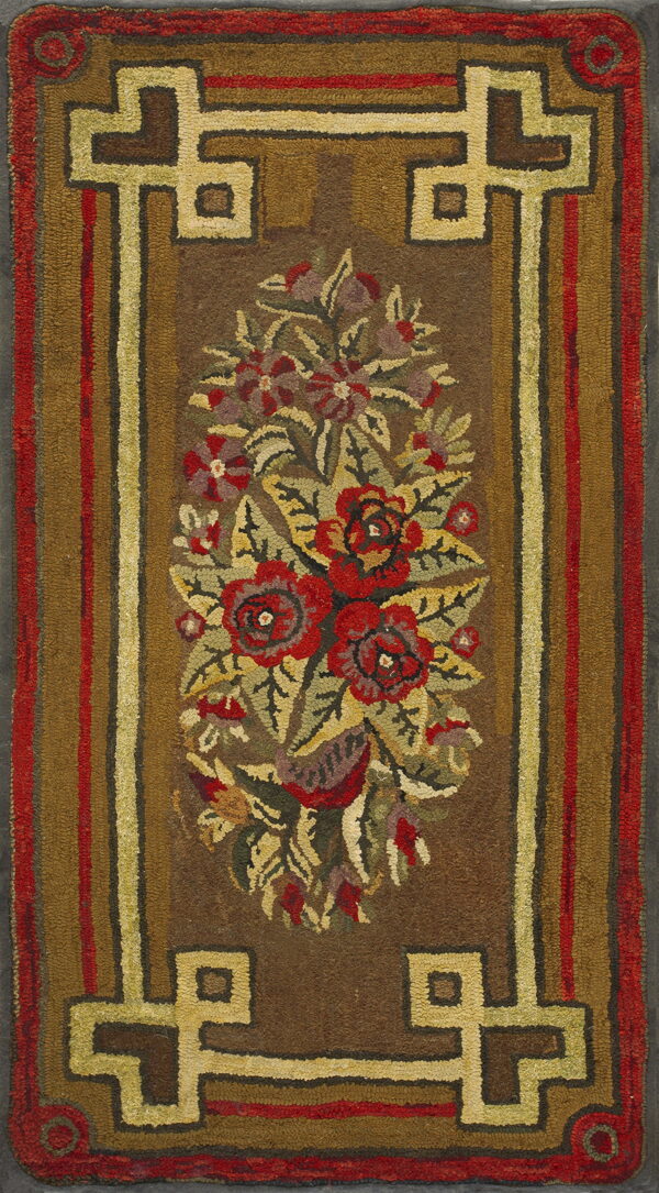 Brown hooked rug displaying a central floral bouquet and geometric fretwork borders in red and gold tones.