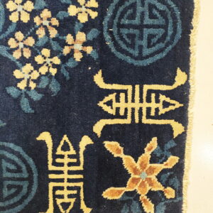 Deep pile navy rug featuring yellow floral sprays, teal symbols, and gold characters on a light tile floor.