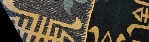 Close-up of a gold and dark blue geometric flatweave pattern beside a solid high-pile section.