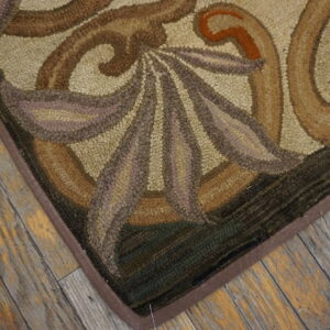 Brown, beige, and green hooked rug with organic motifs rests on textured, distressed wood planks.