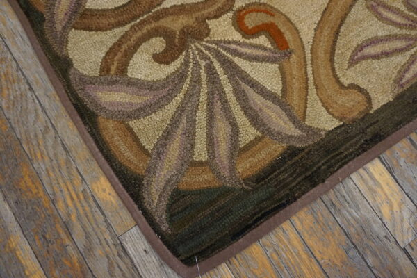 Brown, beige, and green hooked rug with organic motifs rests on textured, distressed wood planks.