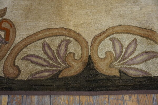 Beige, brown, and mauve floral motif detail on a textured area rug placed on distressed wood flooring.