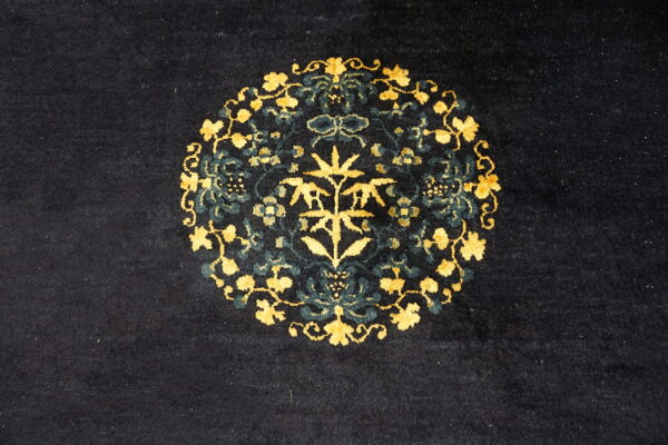 Dark blue rug with a central medallion pattern featuring bright gold and deep teal botanical motifs.