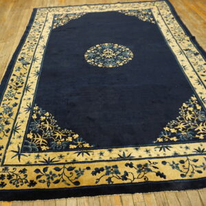 Navy blue rug featuring a circular medallion and elaborate gold and blue floral borders on wood flooring.