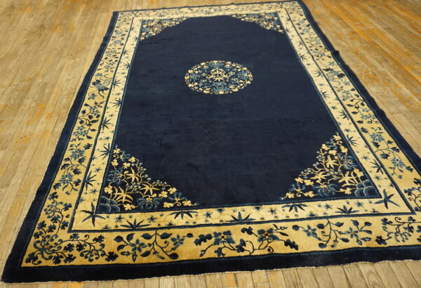 Navy blue rug featuring a circular medallion and elaborate gold and blue floral borders on wood flooring.