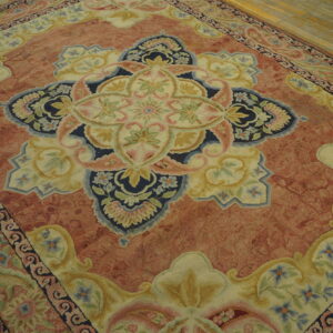 Ornate floral medallion rug in rust, navy, cream, and pink on wide plank wood flooring.