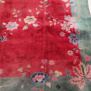 Red and green rug with a plush texture and scattered pastel floral motifs.